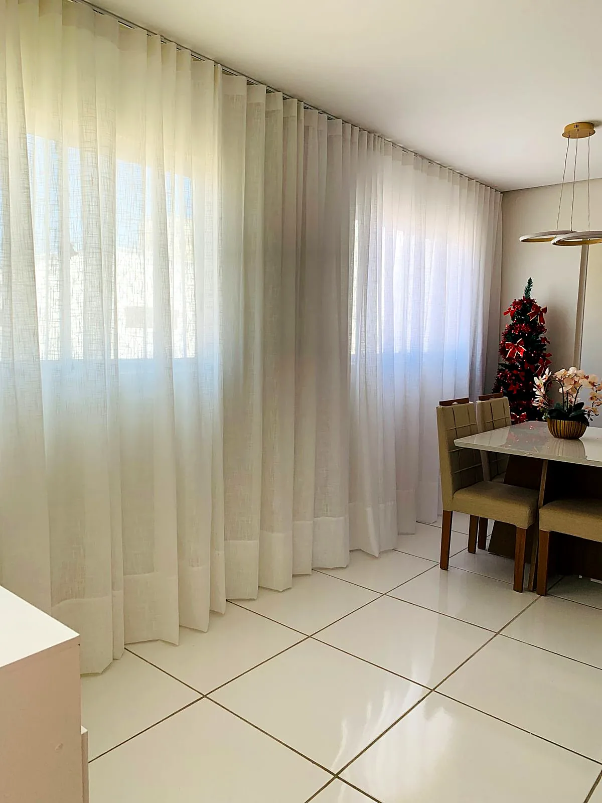 Cortina de tecido translúcido em sala de jantar com mesa de madeira