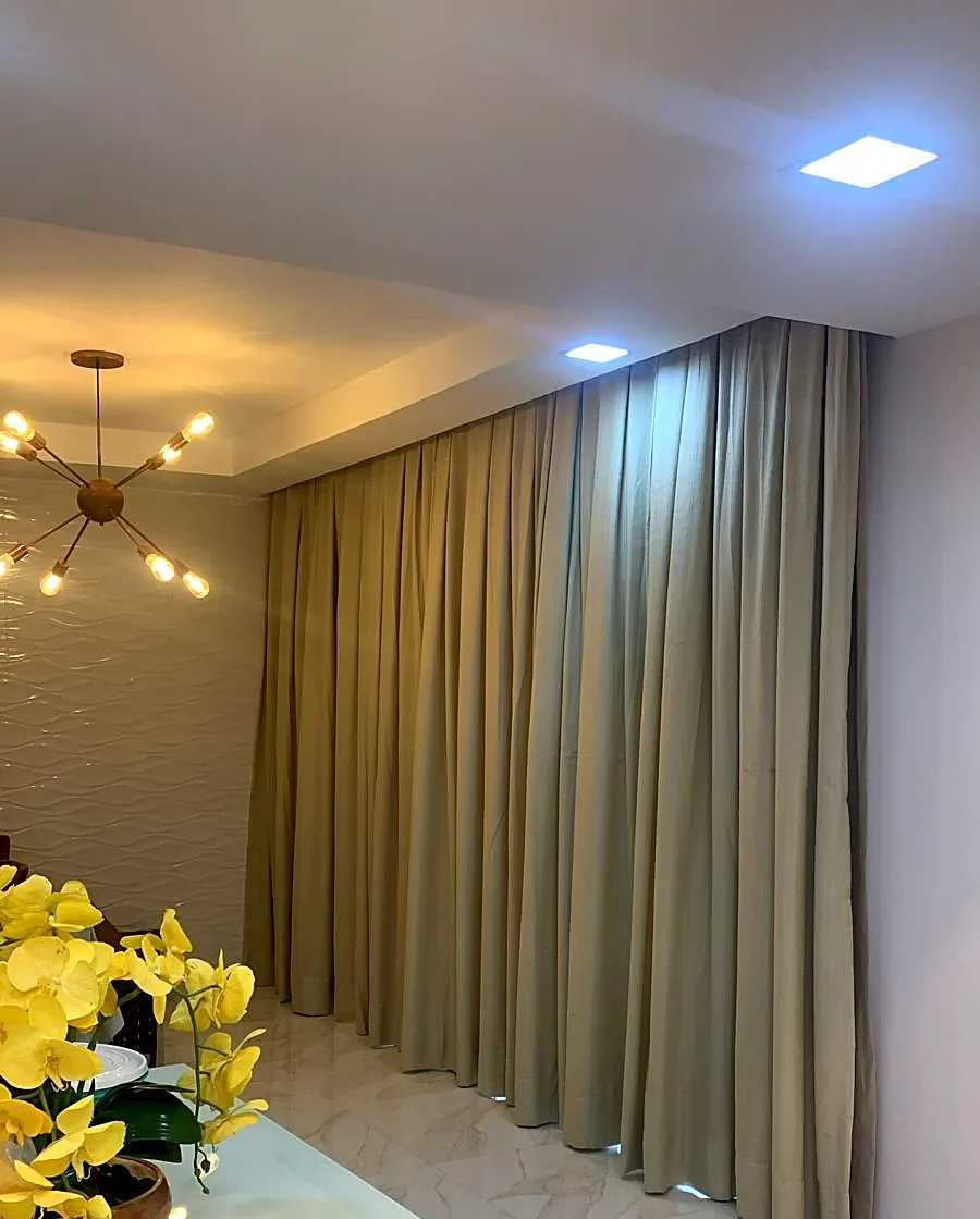 Cortina de tecido bege em sala de jantar com arranjo de flores amarelas