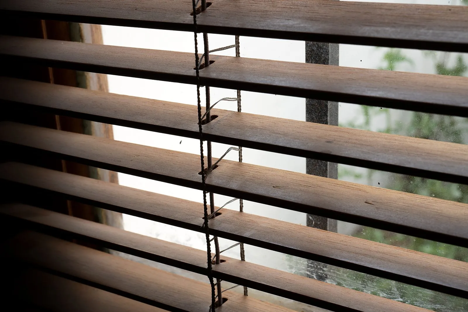 Detalhe das lâminas de madeira e dos cordões de uma persiana horizontal