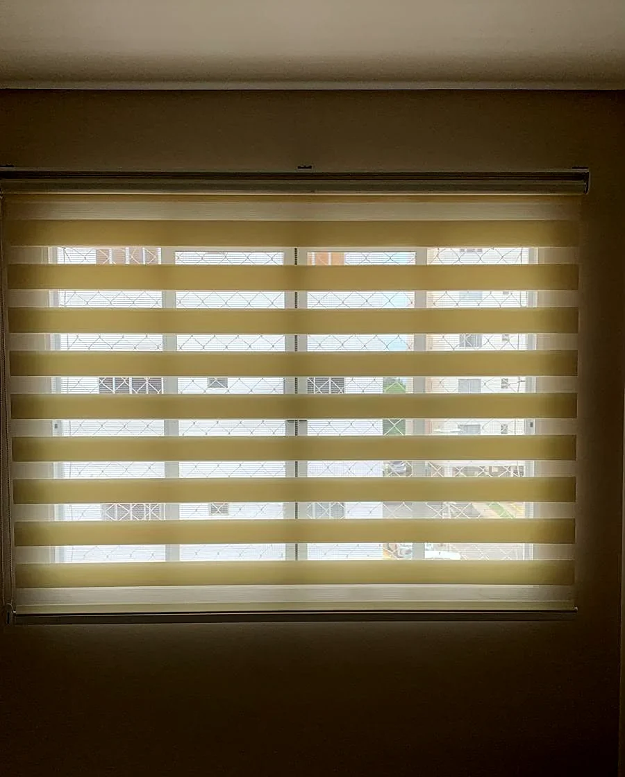 Persiana double vision com faixas abertas deixando a luz passar em quarto