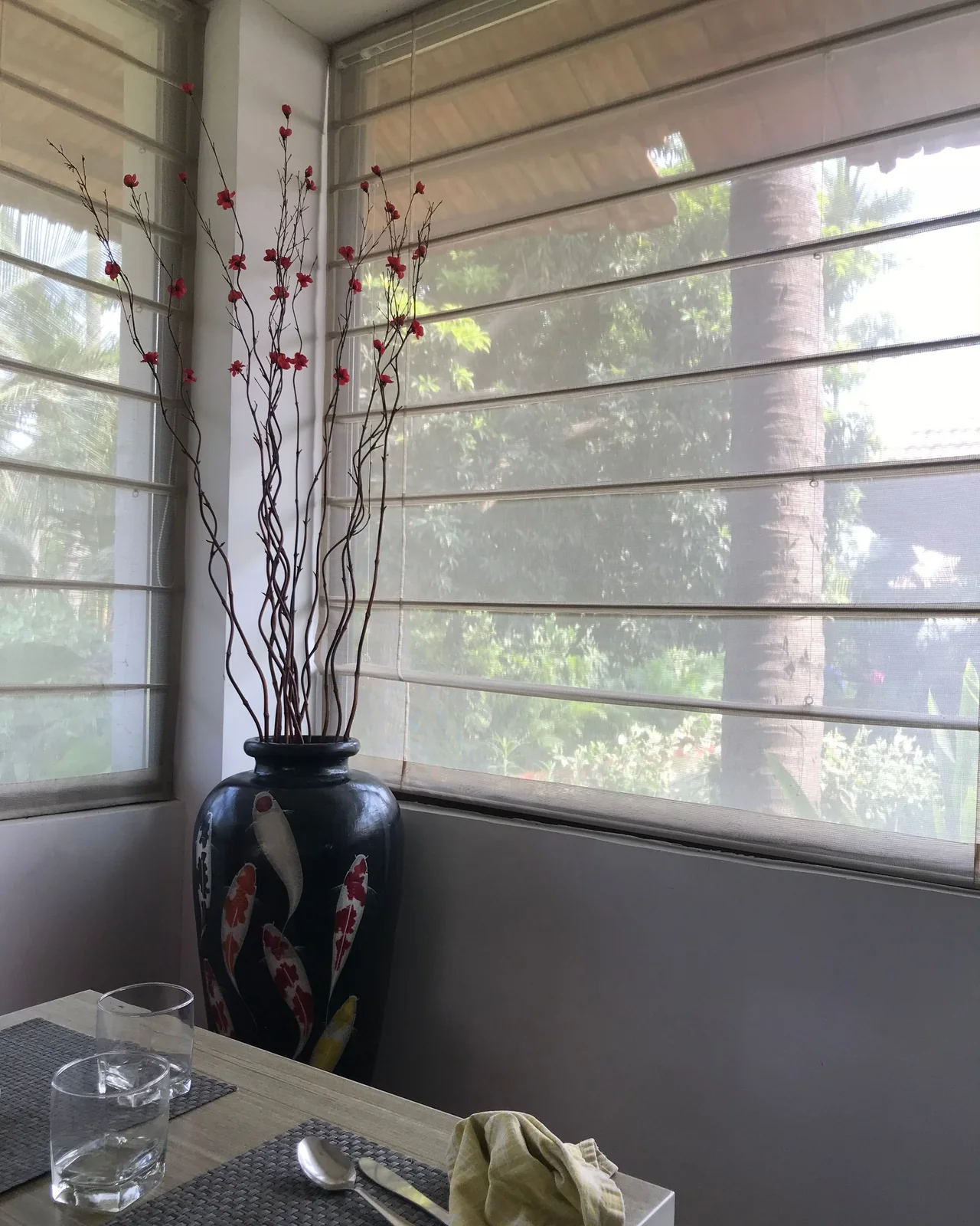 Persiana romana cinza com gomos horizontais em janela de canto com vaso decorativo